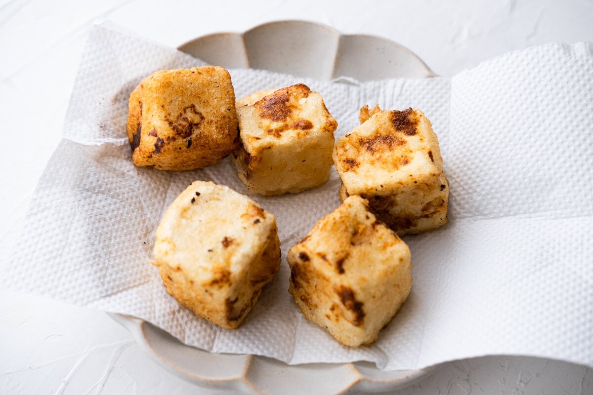 Deep-fried tofu on a plated lined with paper towels. 