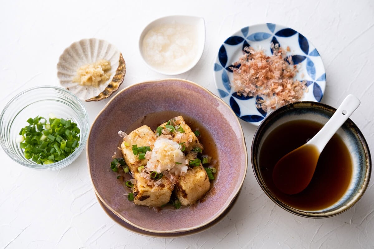 Agedashi tofu with tentsuyu sauce, grated daikon, scallions, and dried bonito flakes garnished on top. 