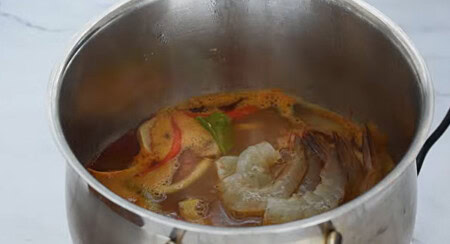 Boiling tom yum soup with shrimp, mushrooms, herbs, and seasonings.