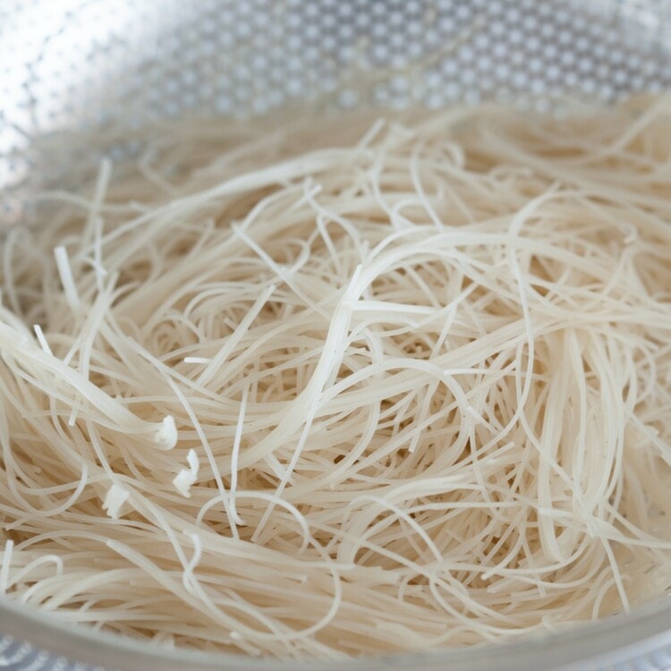 Rice noodles in a colander.