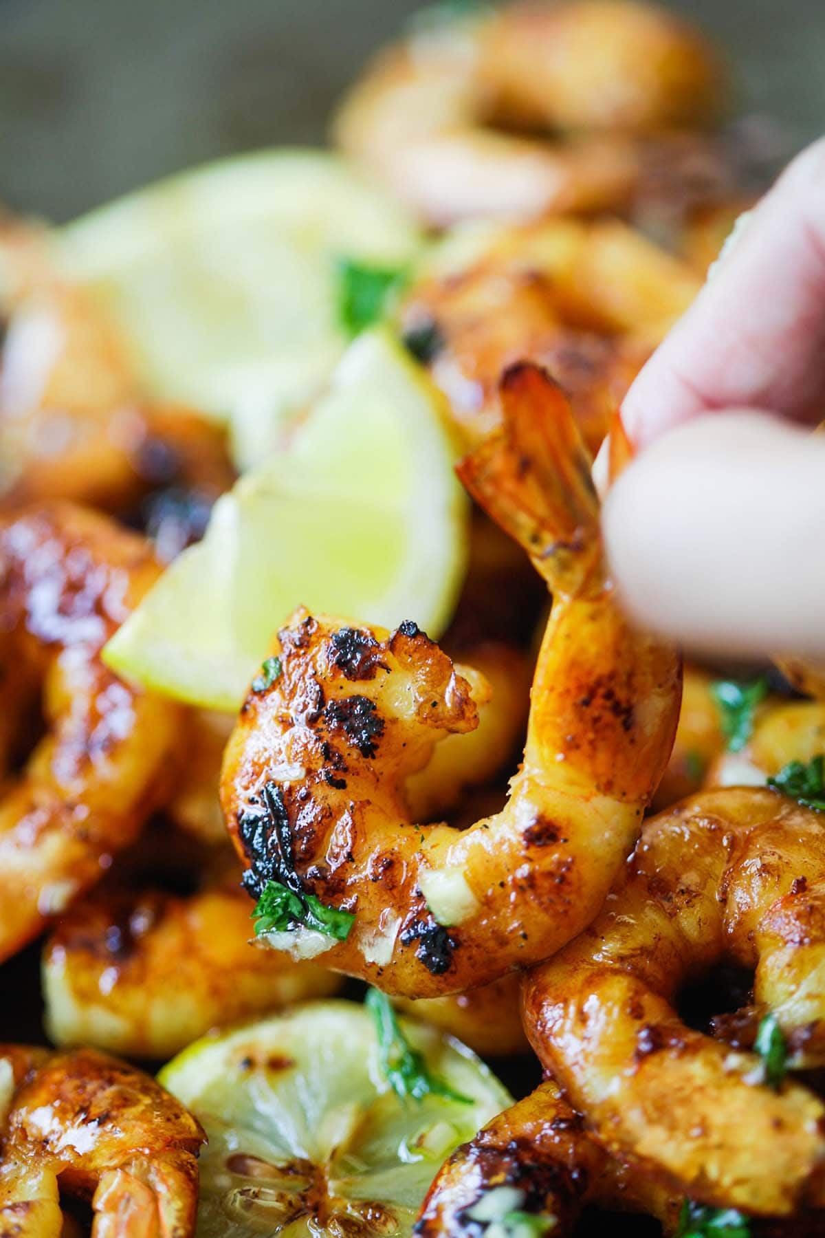 Cajun grilled shrimp with honey Cajun glaze picked up by a hand. 