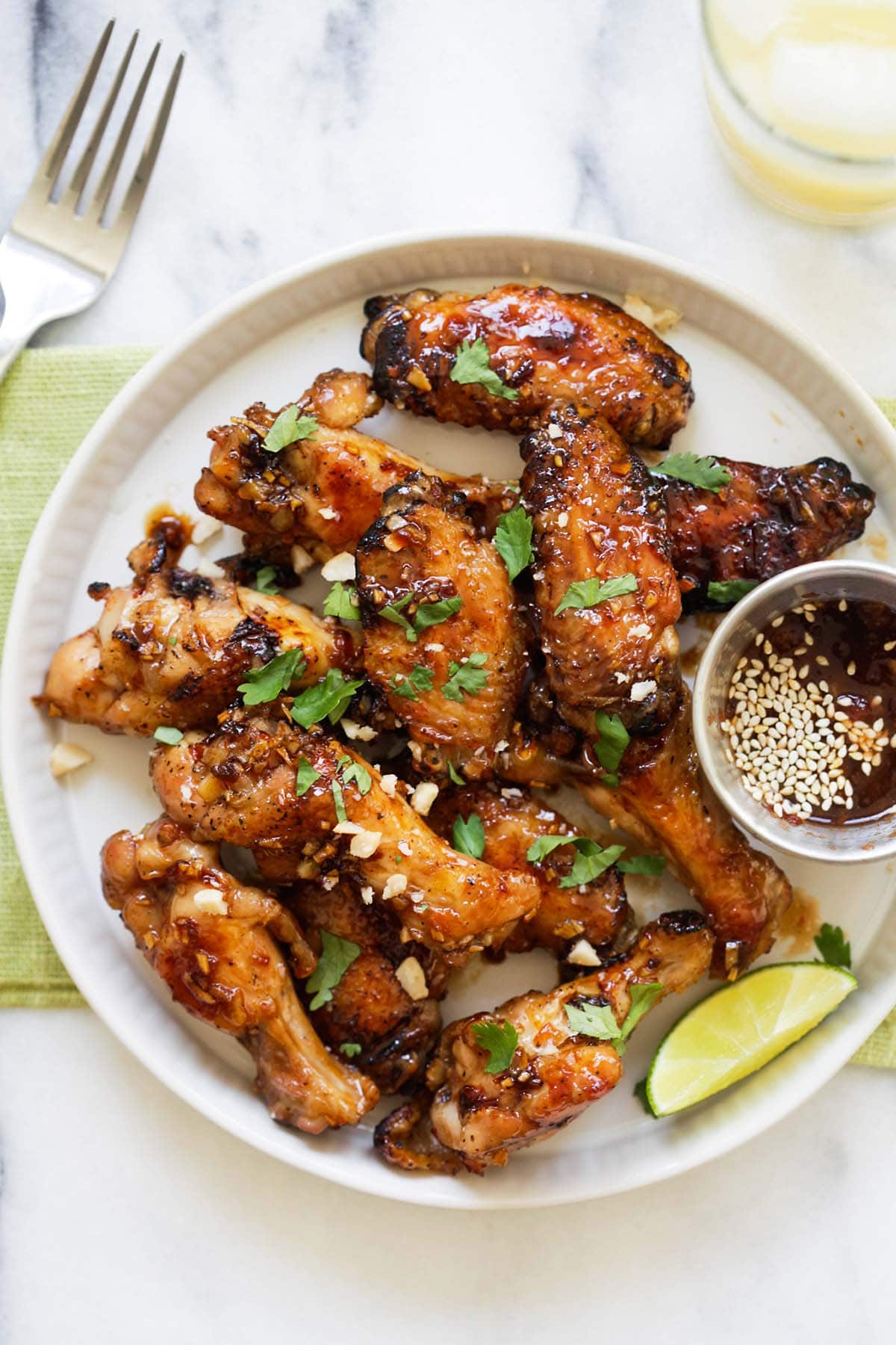 Sticky Asian chicken wings coated with savory, sweet and sticky honey garlic chili glaze in a plate.