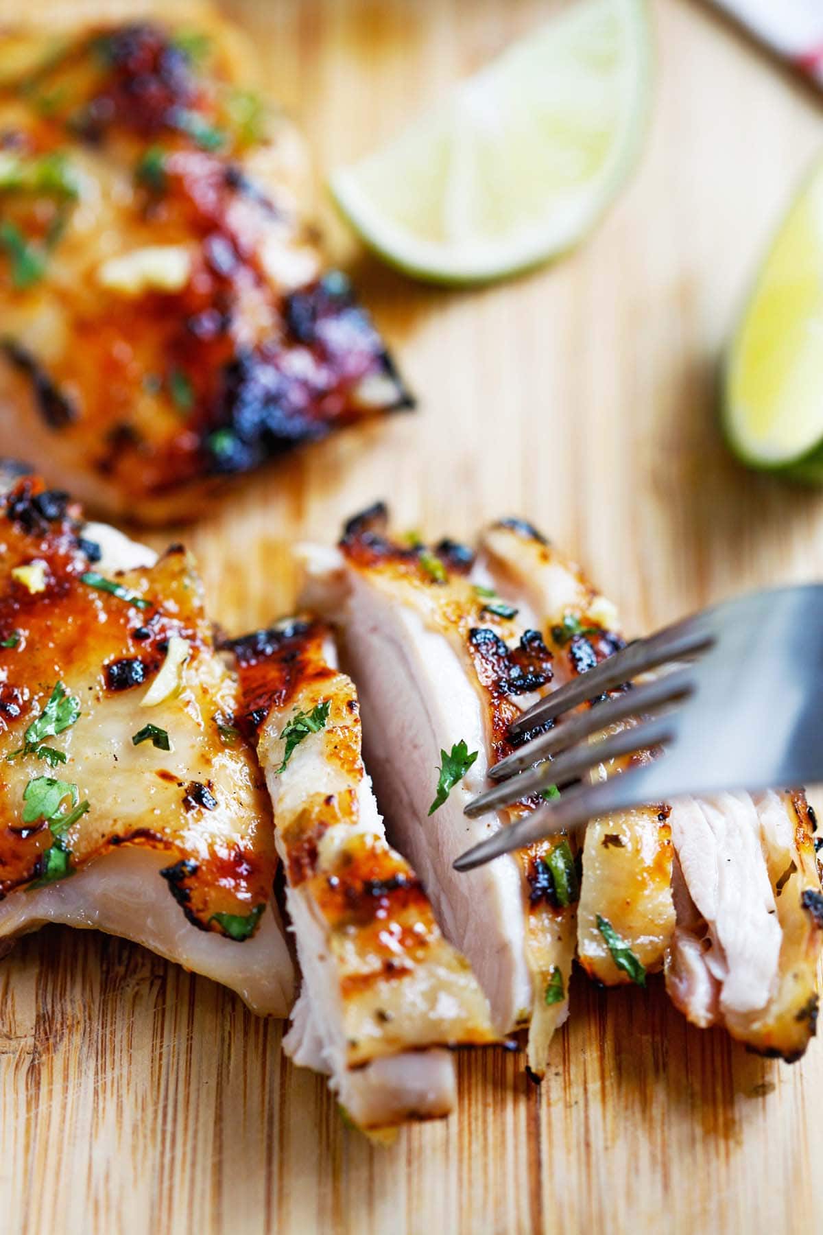 Asian style Chili lime chicken featuring grilled chciken sliced and ready to serve on a wooden chopping board.