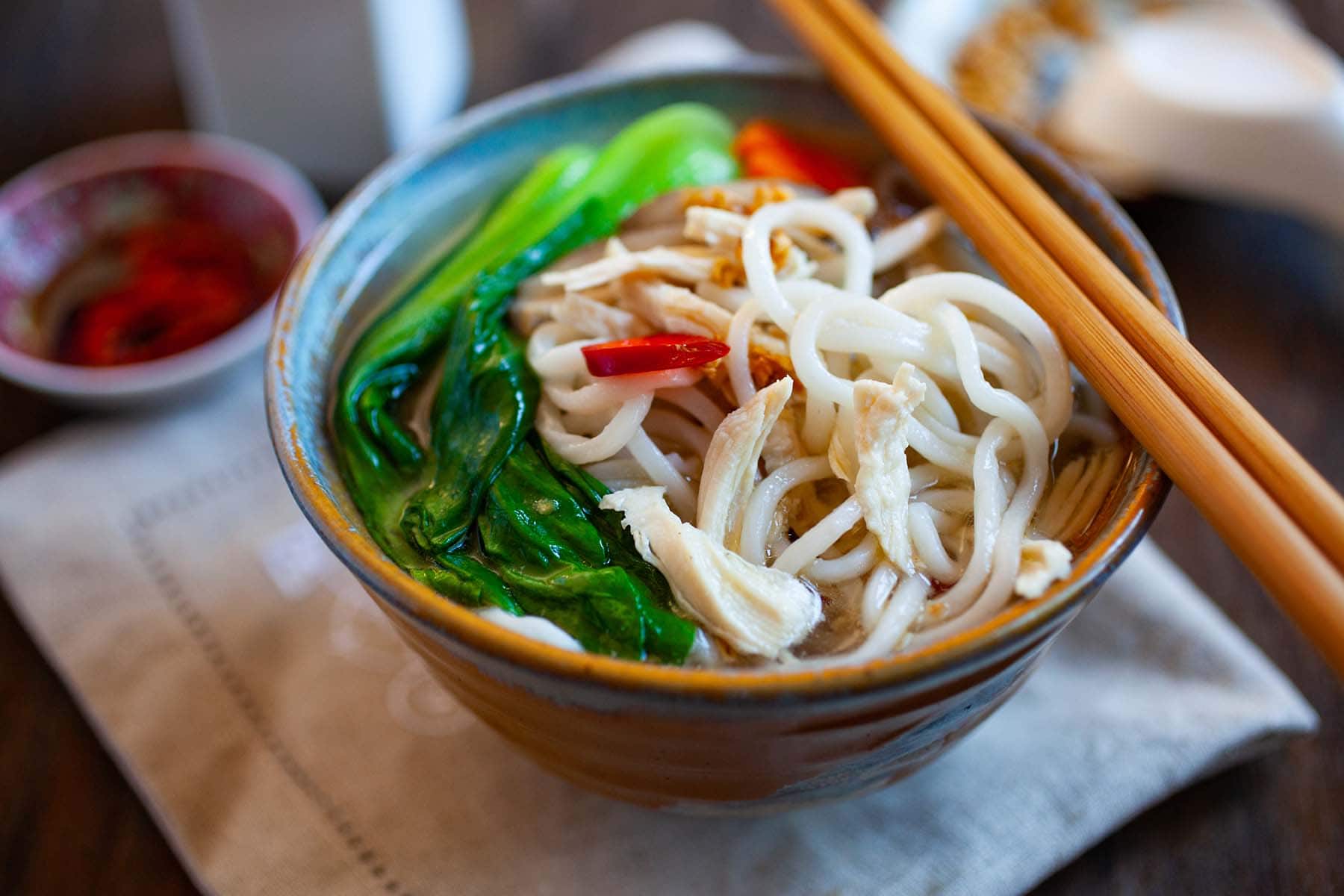 Chinese noodle soup with chicken, bok choy and noodles in a white bowl.