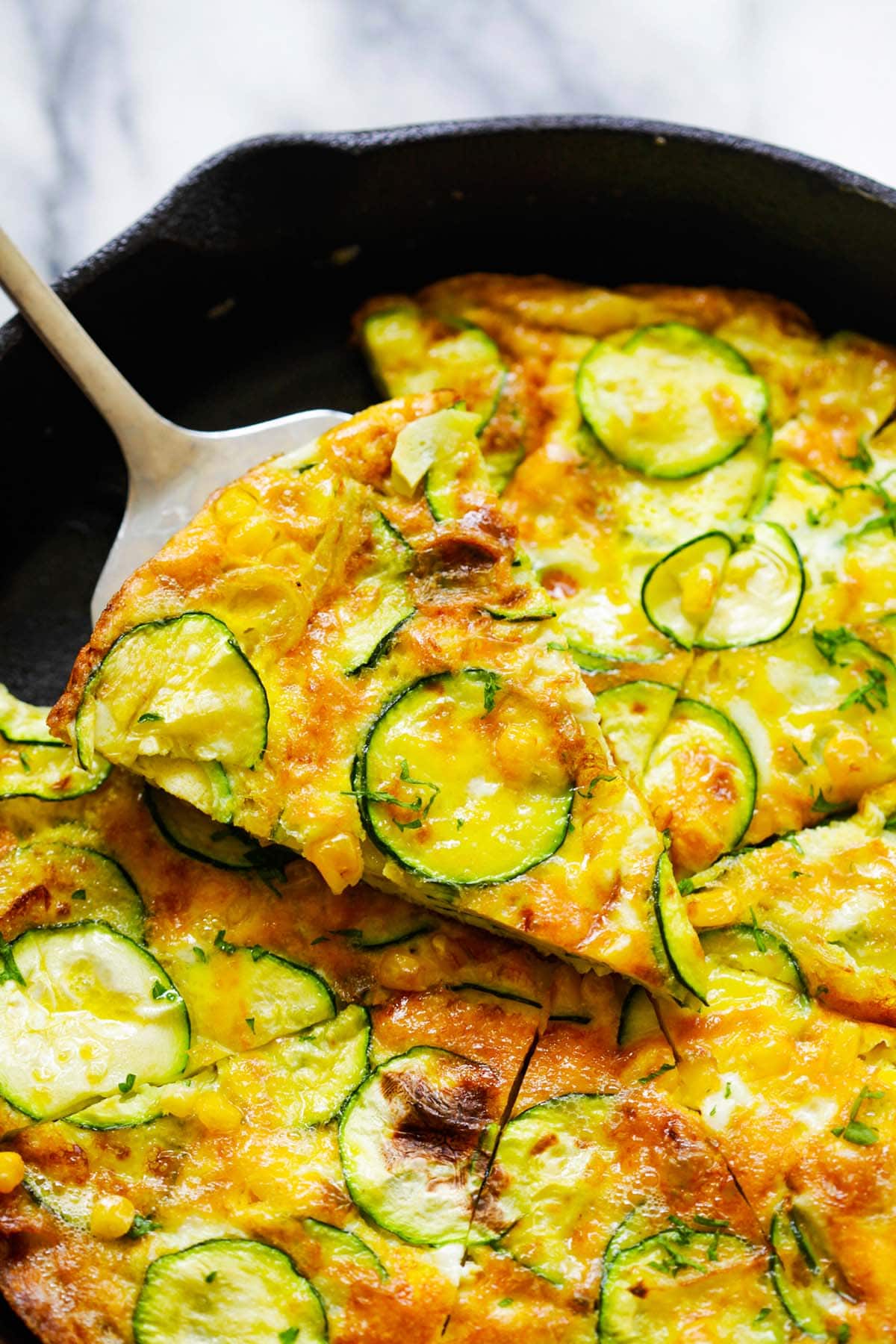 A slice of delicious frittata recipe made with zucchini and corn on a pizza shovel.