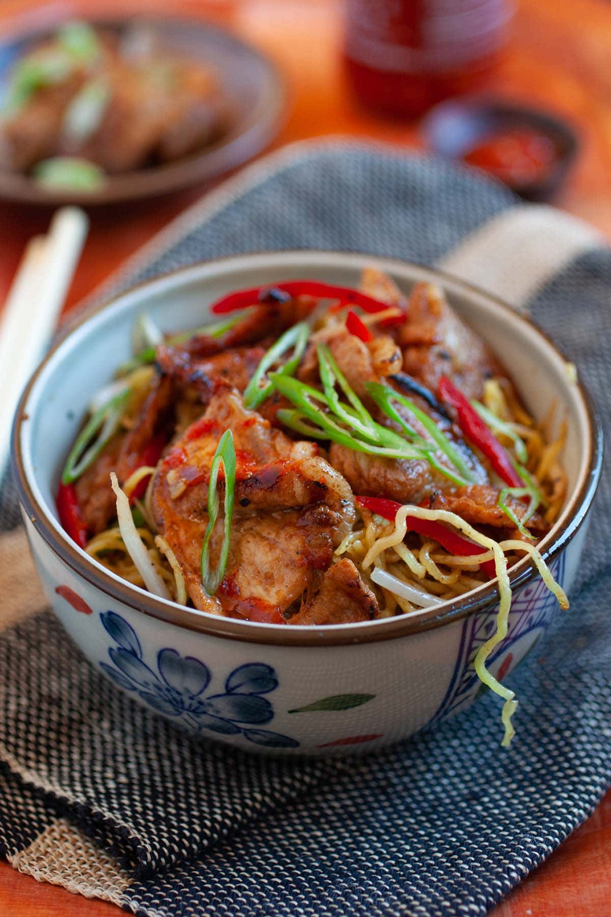Easy authentic sweet and sour pork on top of stir fry noodles served in a bowl.