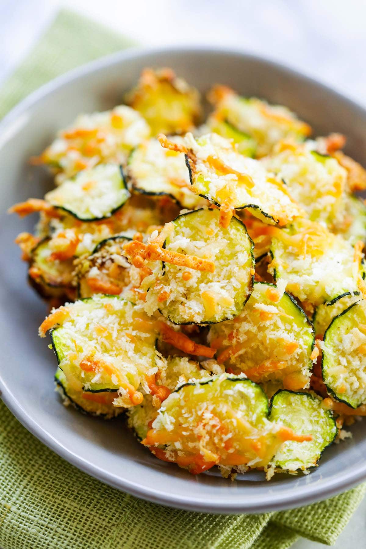 Golden-brown zucchini chips topped with Parmesan ready to serve.