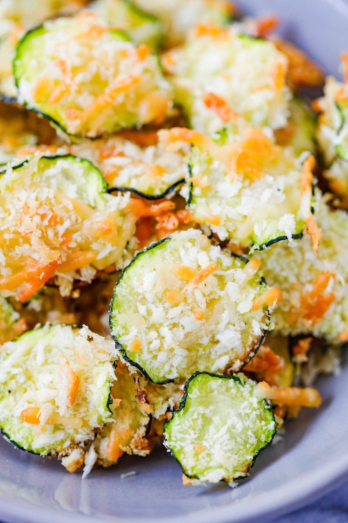 Crispy and flavorful baked zucchini chips coated with parmesan in a bowl.