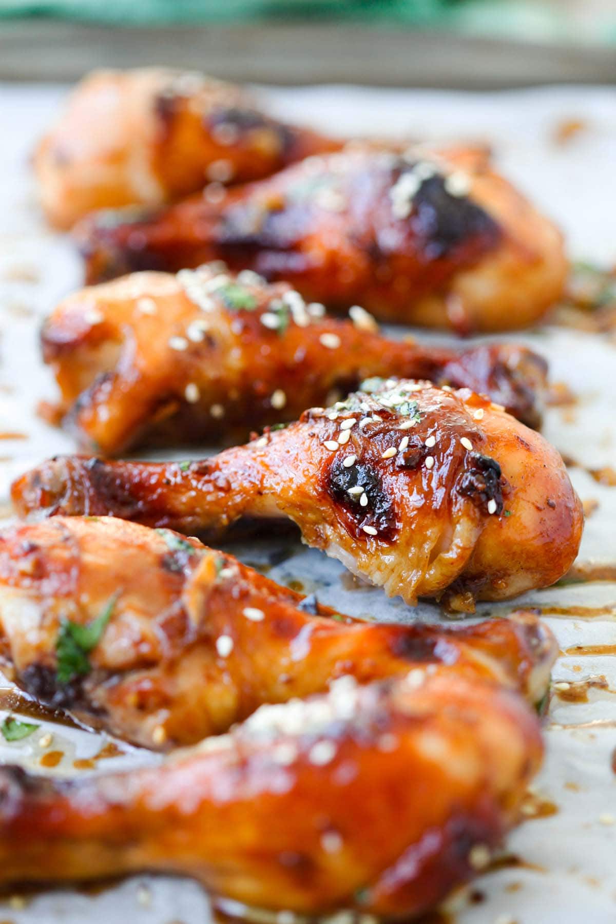 Chicken drumsticks coated in hoisin sauce on an aluminium foil.