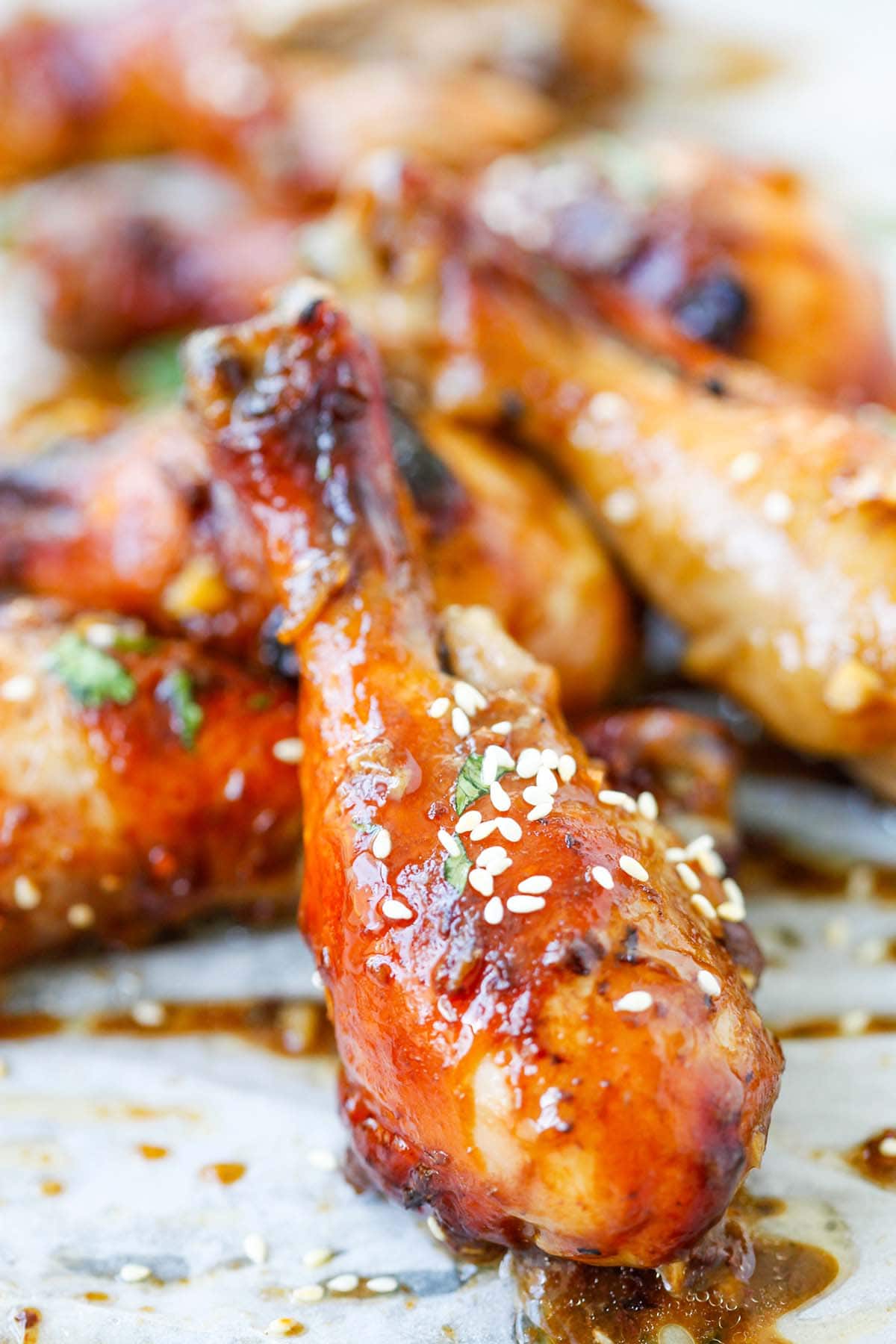 Hoisin-infused baked chicken drumsticks with golden-brown glaze on a baking sheet. 