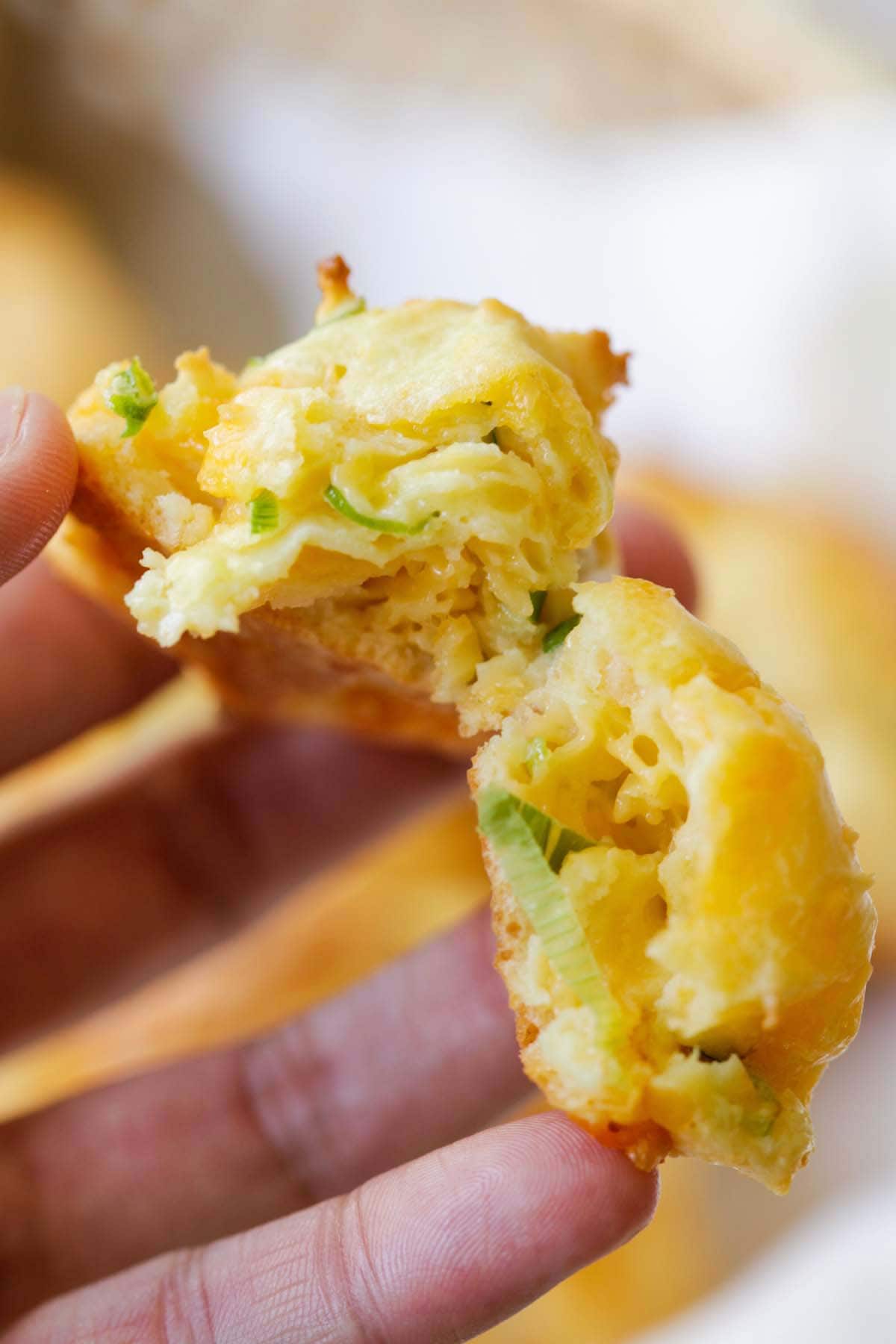 Buttery homemade French Cheddar Cheese Puffs split in half and held by a hand.