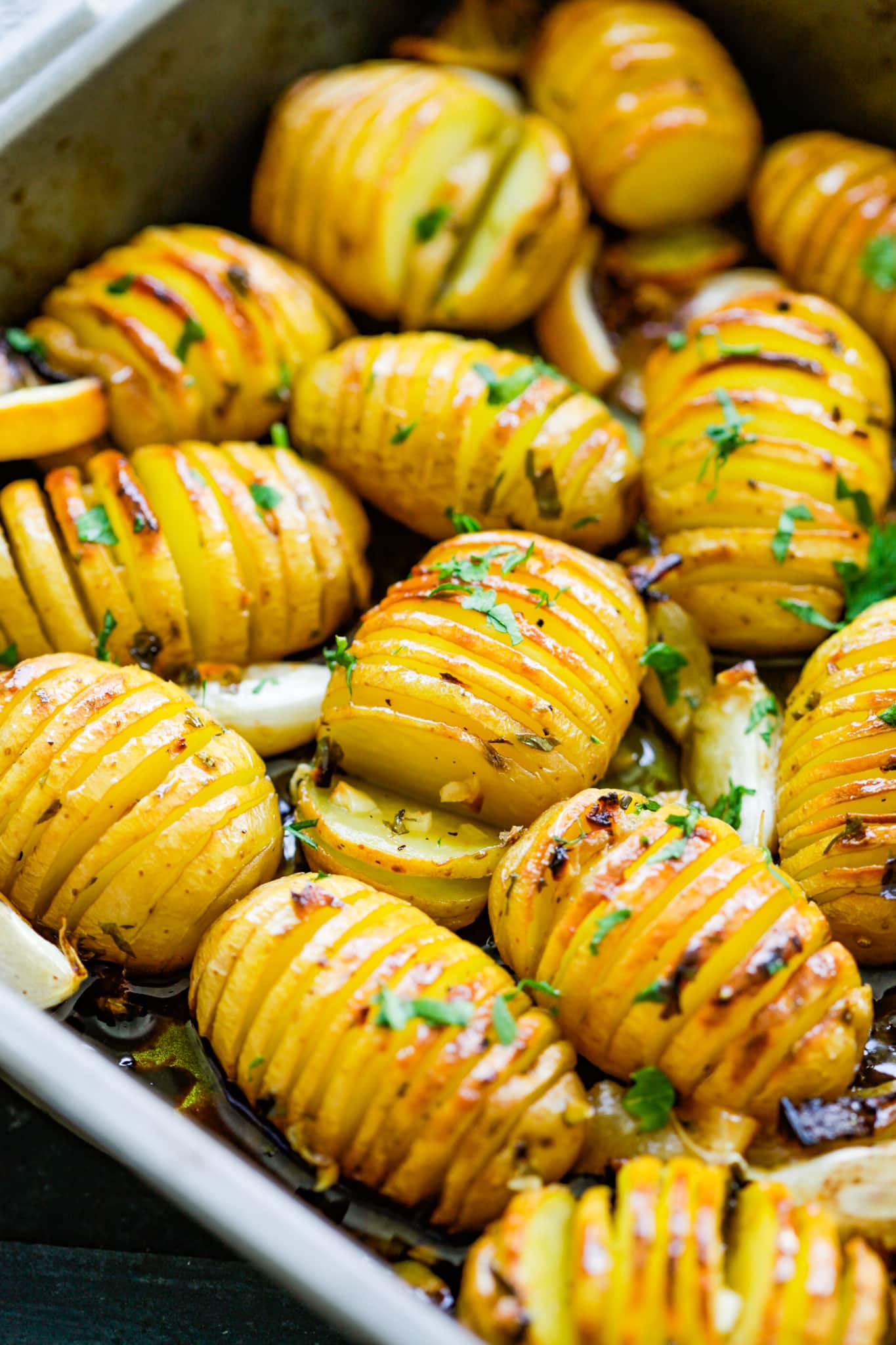Homemade roasted potatoes loaded with butter, lemon, garlic and herb in a baking ware.