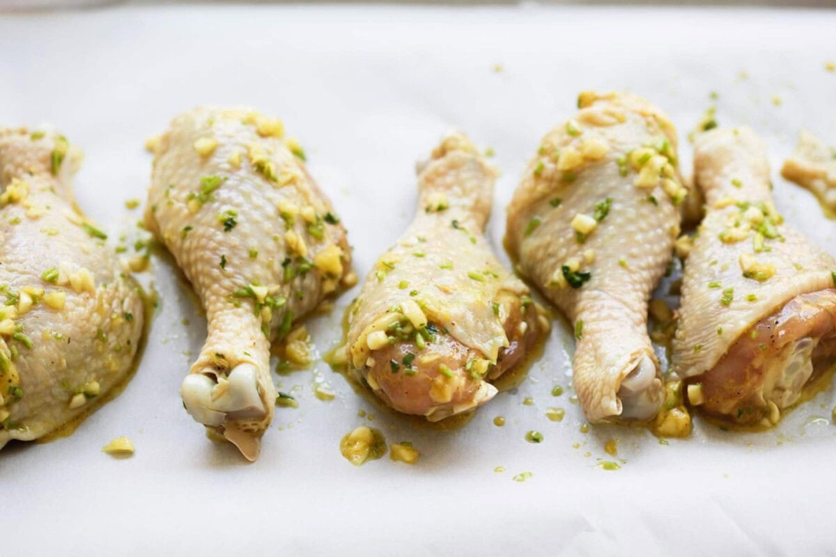 Chicken drumsticks coated in Thai marinade on parchment paper.