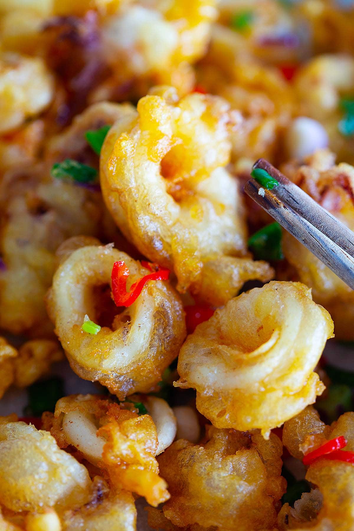 Close up shot of a chopstick with crispy golden brown fried squids.