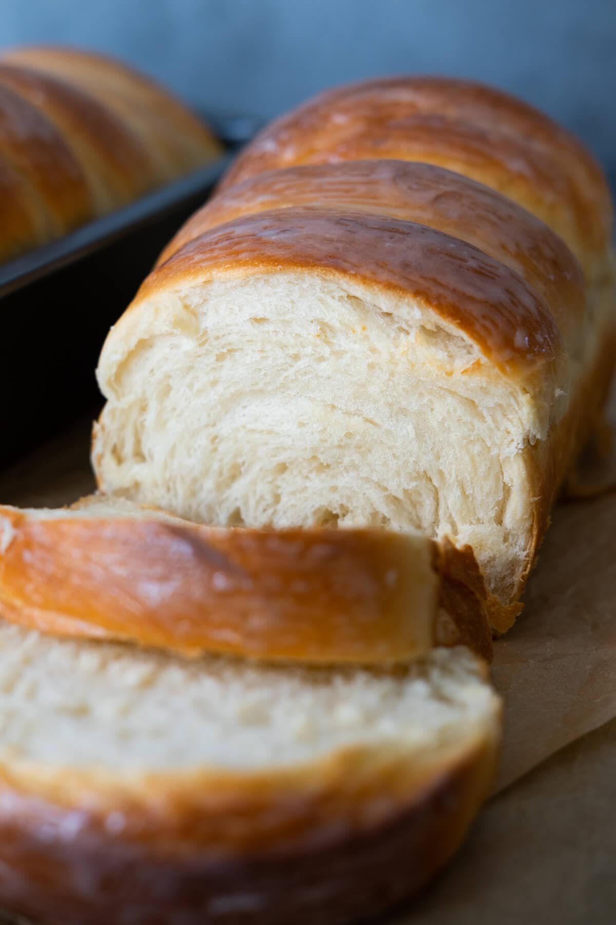 A close up shot of a cut up bread with condensed milk coated exterior and soft white fluffy interior. 