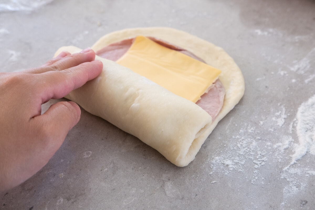 Shape the dough and roll up the fillings to make the ham and cheese loaf