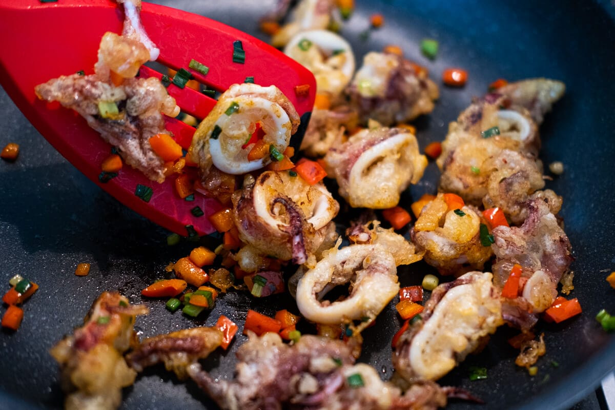 Stir-fry the scallion, red chilies and deep-fried squid on a pan. 