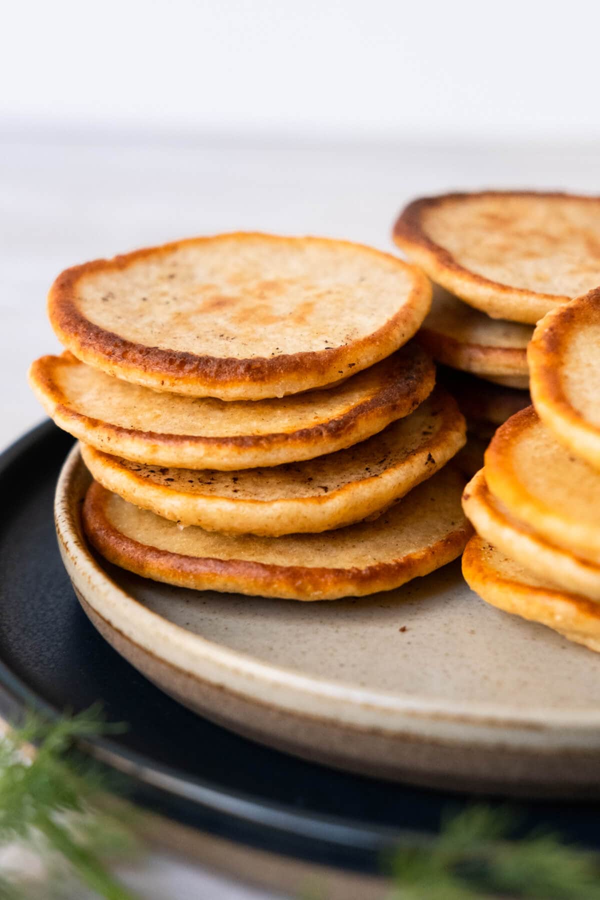 A close-up view of a plate of delightful arrangement of small Russian pancakes with sprinkle of fresh herbs. 