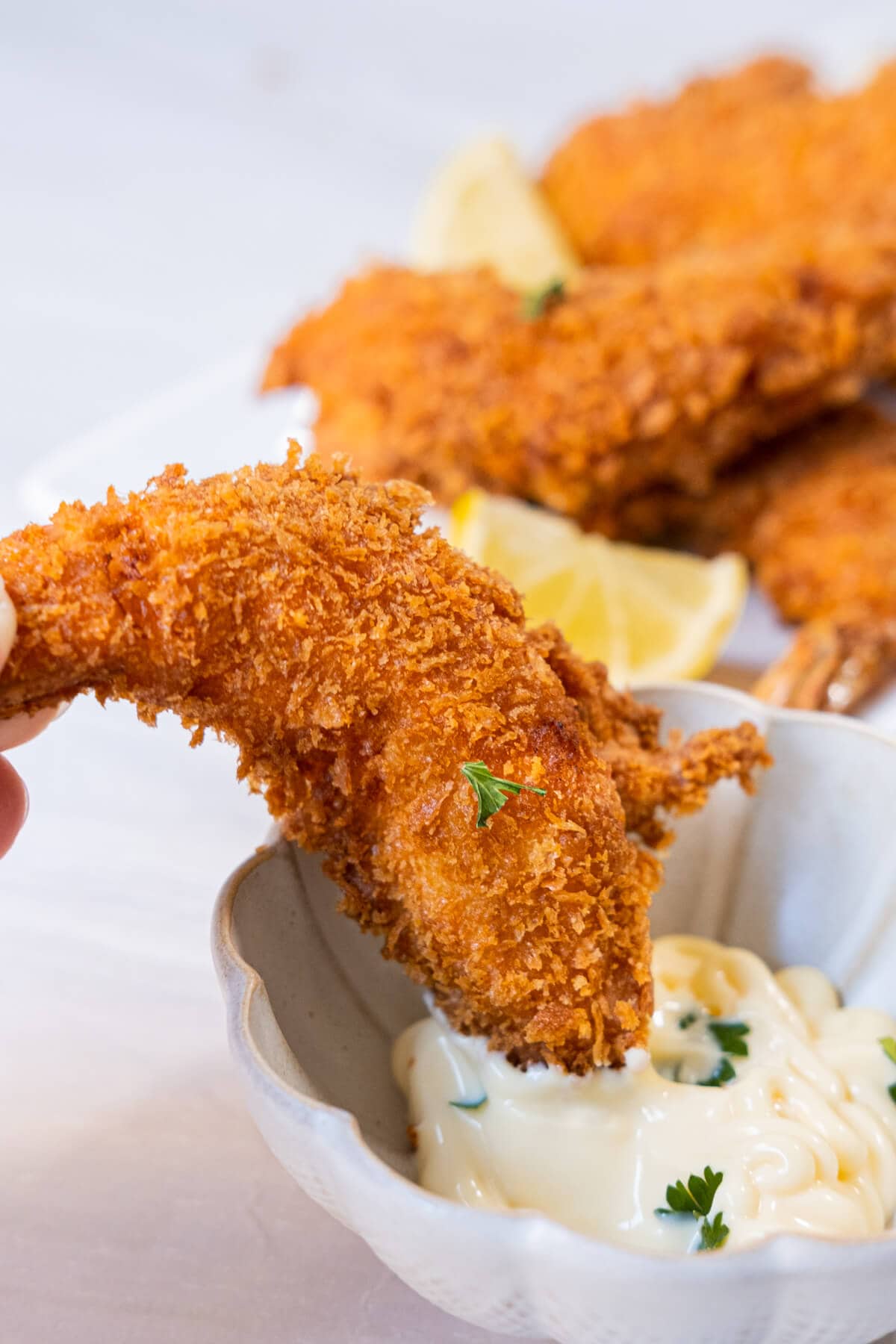 A deep fried battered shrimp being dipped into Japanese mayonnaise Kewpie sauce. 