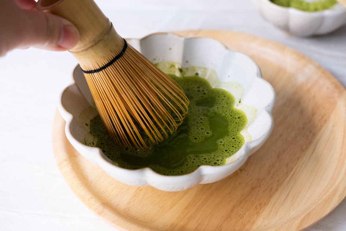 Dissolving matcha powder with hot water in a small bowl. 