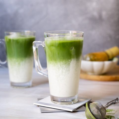 Two iced matcha latte with a beautiful layer of green and white in the glass.