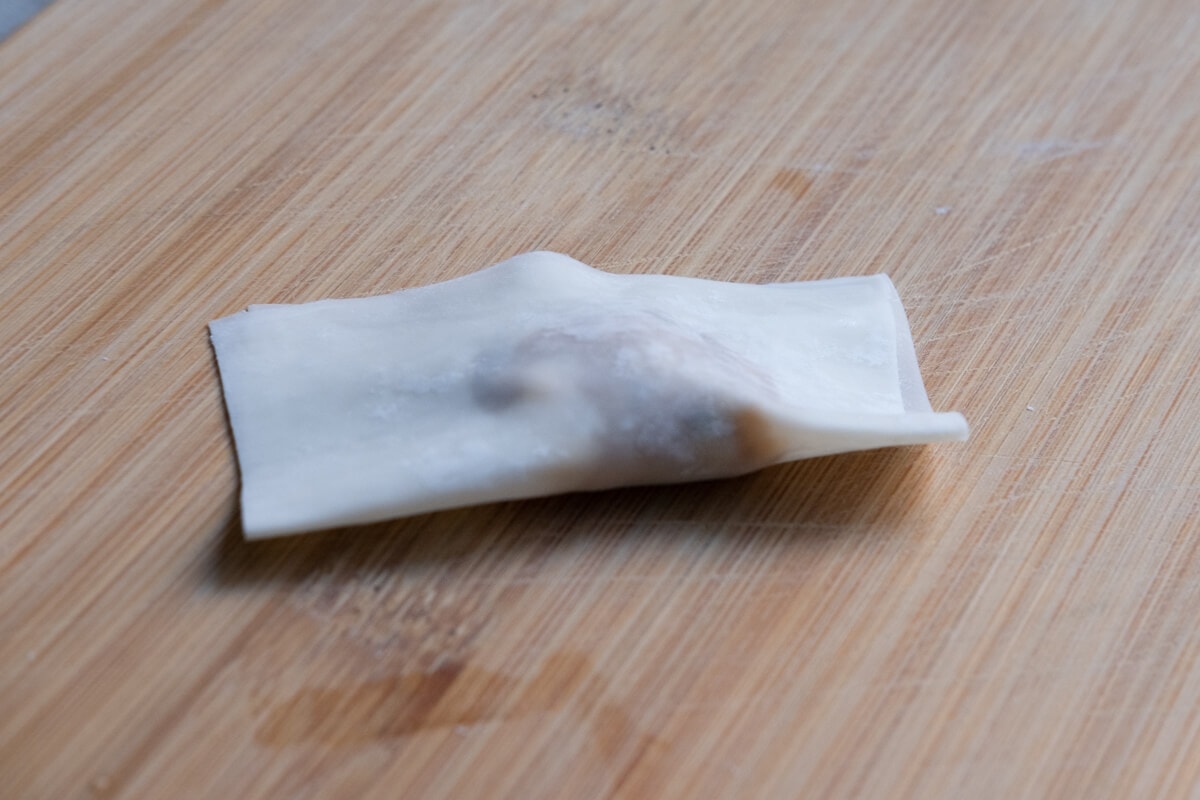 Wrapping a chicken wonton with a wonton wrapper.