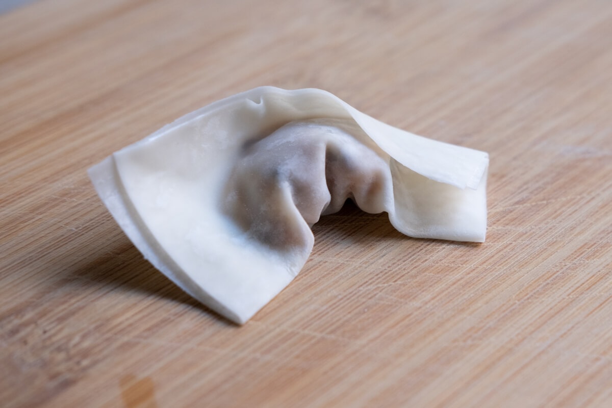 Folding a chicken wonton with filling.