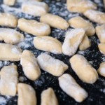 Soft potato gnocchi on a black stone board with flour dust on top.