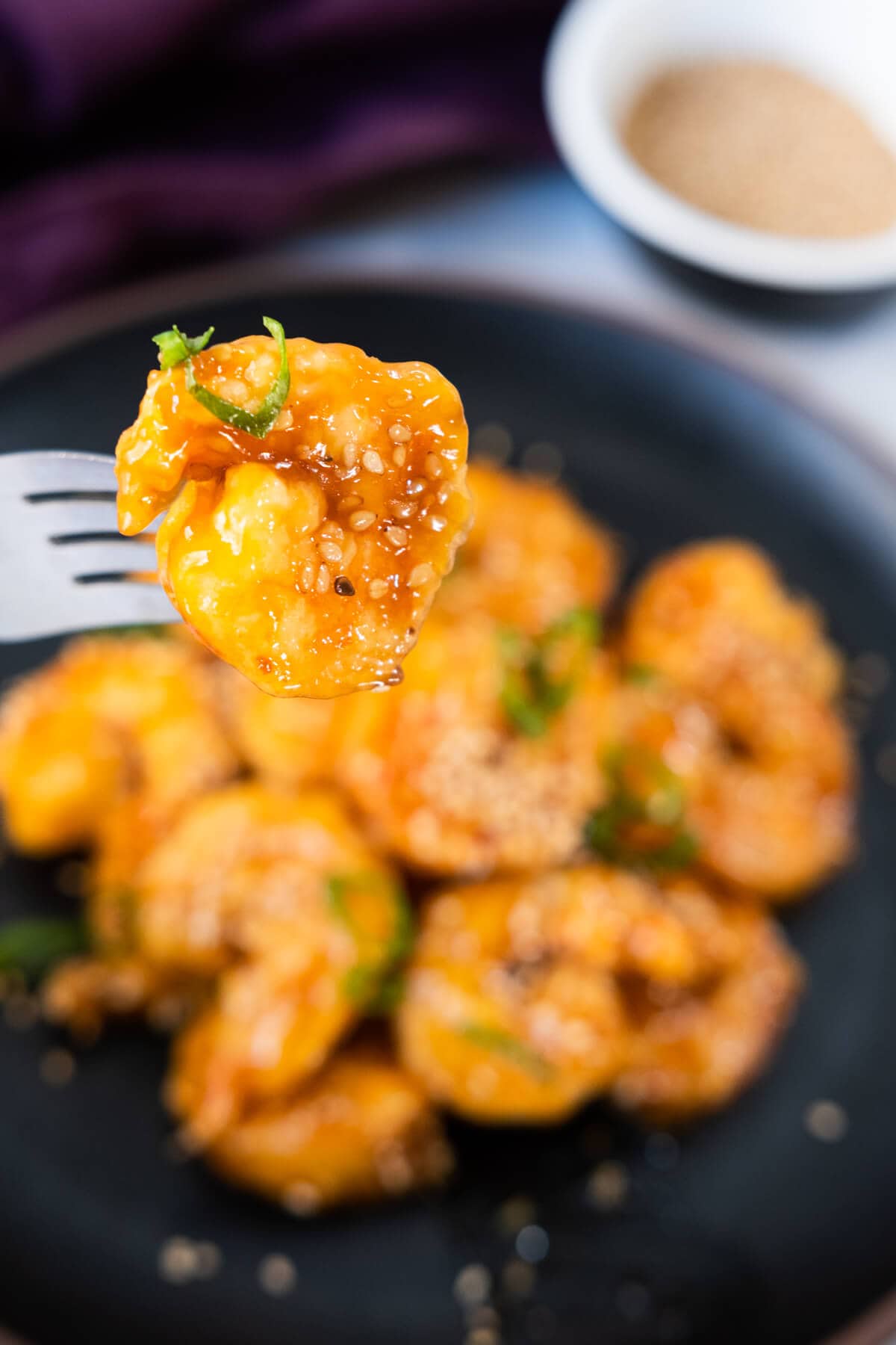 A fork picking up a big sesame shrimp.