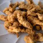 Crispy fried pork shoulder strips on a white plate.