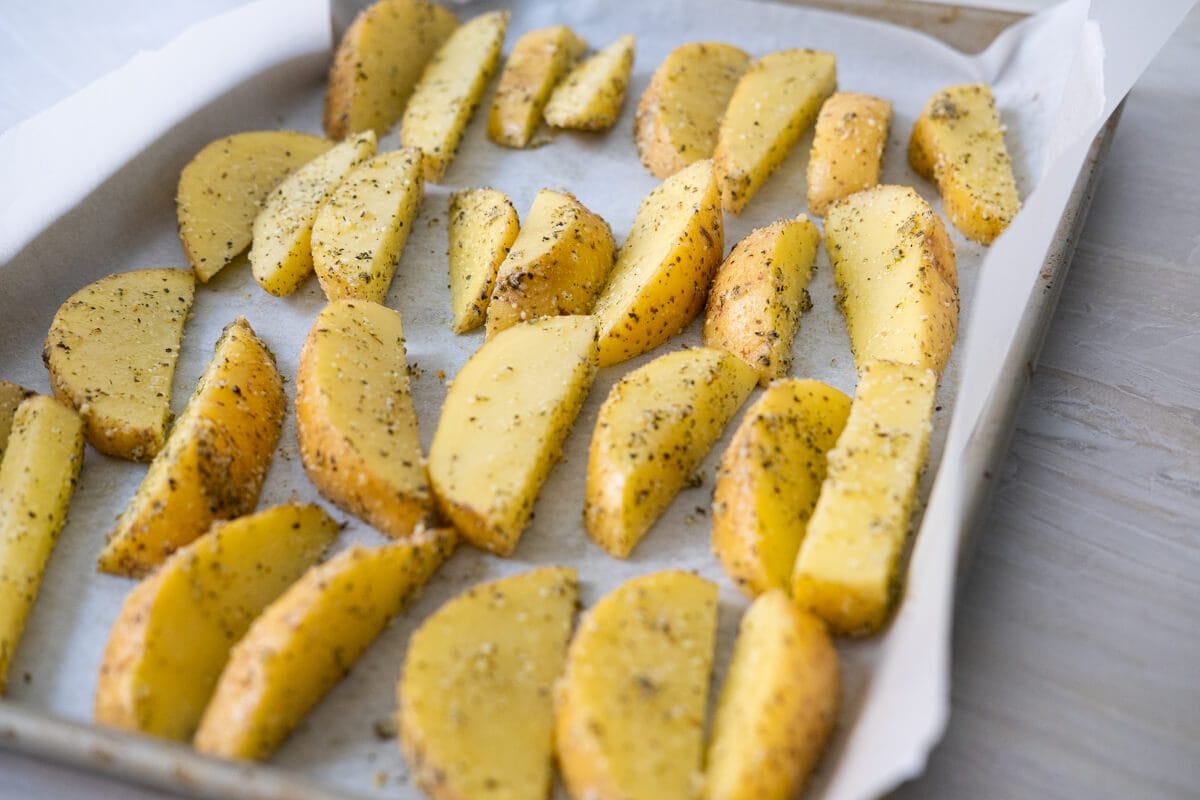 Place seasoned potato wedges on a baking tray lined with parchment paper in a single layer. 