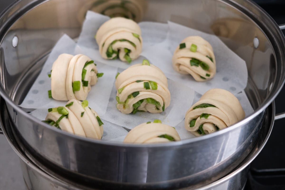 Seven shaped doughs are placed in the parchment lined steamer.