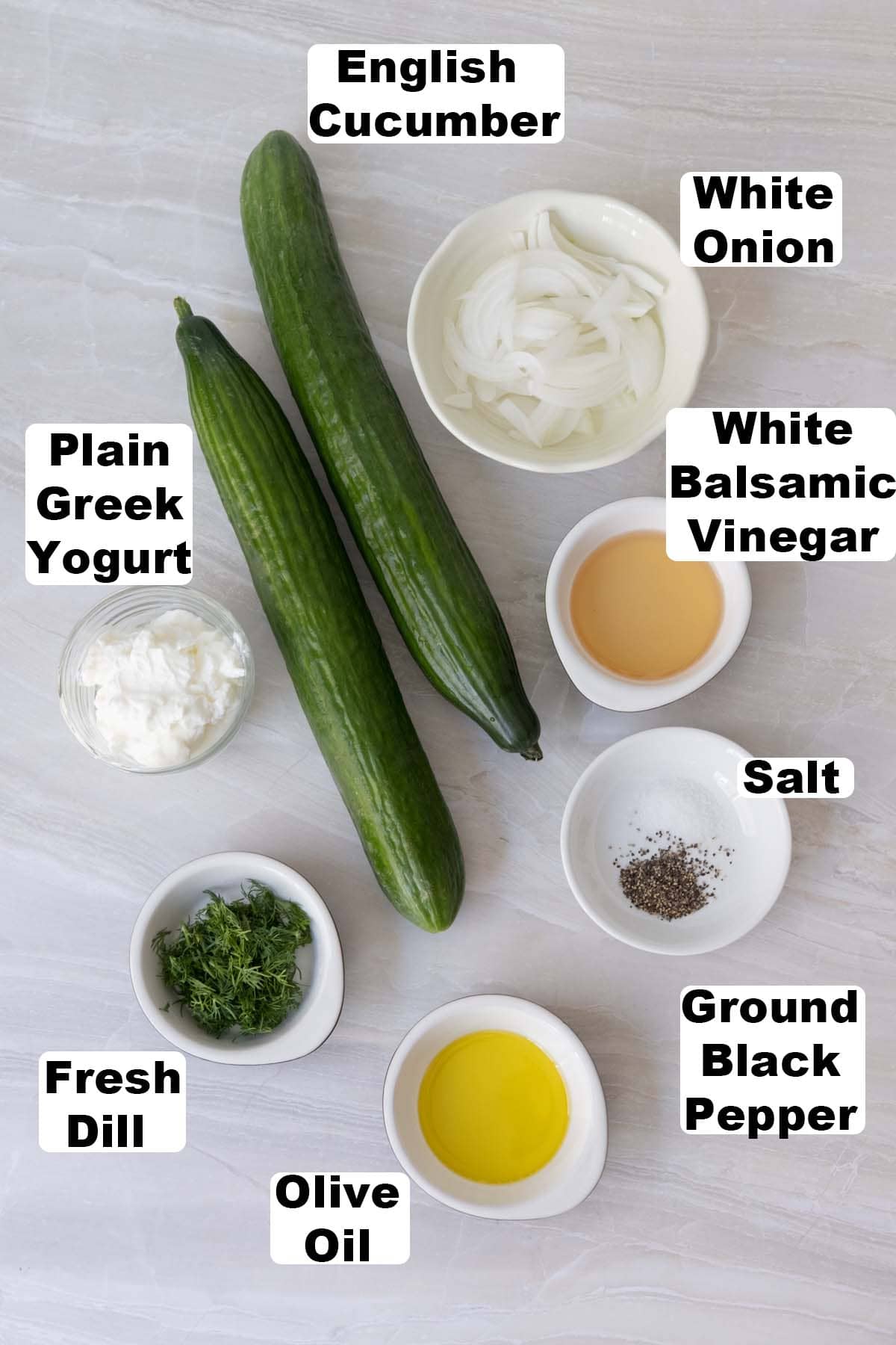 Creamy cucumber salad ingredients: English cucumber, plain greek yogurt, fresh dill, white onion, white balsamic vinegar, salt, ground black pepper and olive oil.