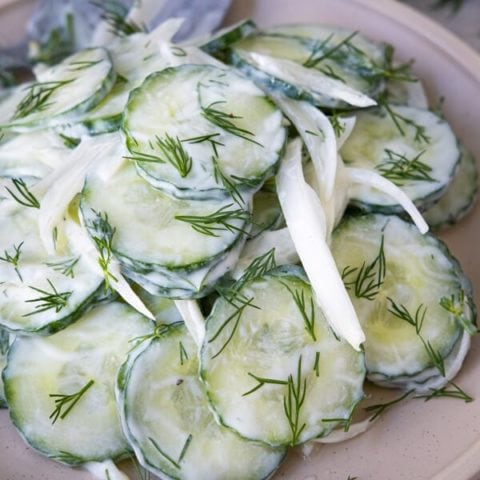 Creamy cucumber salad with white onion and garnished with fresh chopped dill.