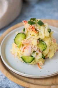 Japanese potato salad on a white plate and stack on another wooden plate.