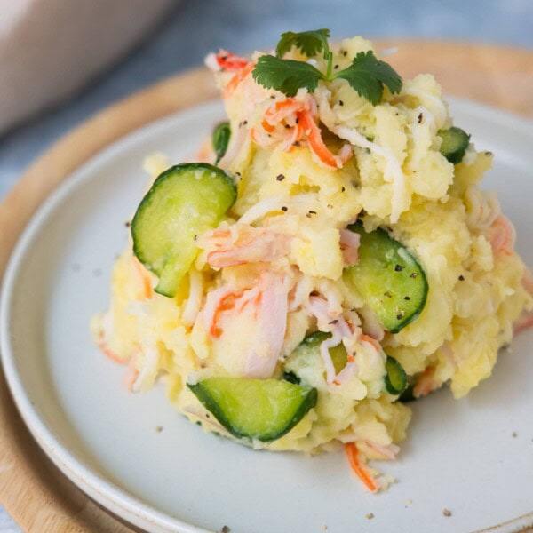 Japanese potato salad on a white plate and stack on another wooden plate.