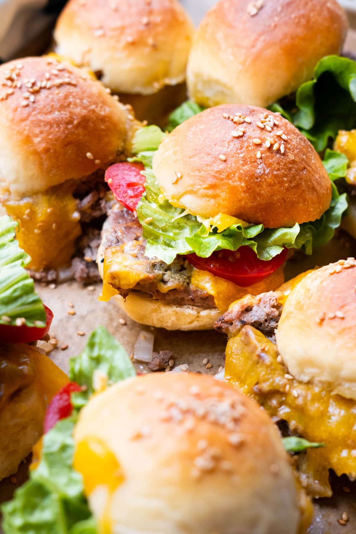 Mini cheeseburger sliders with lettuce and tomato slices.