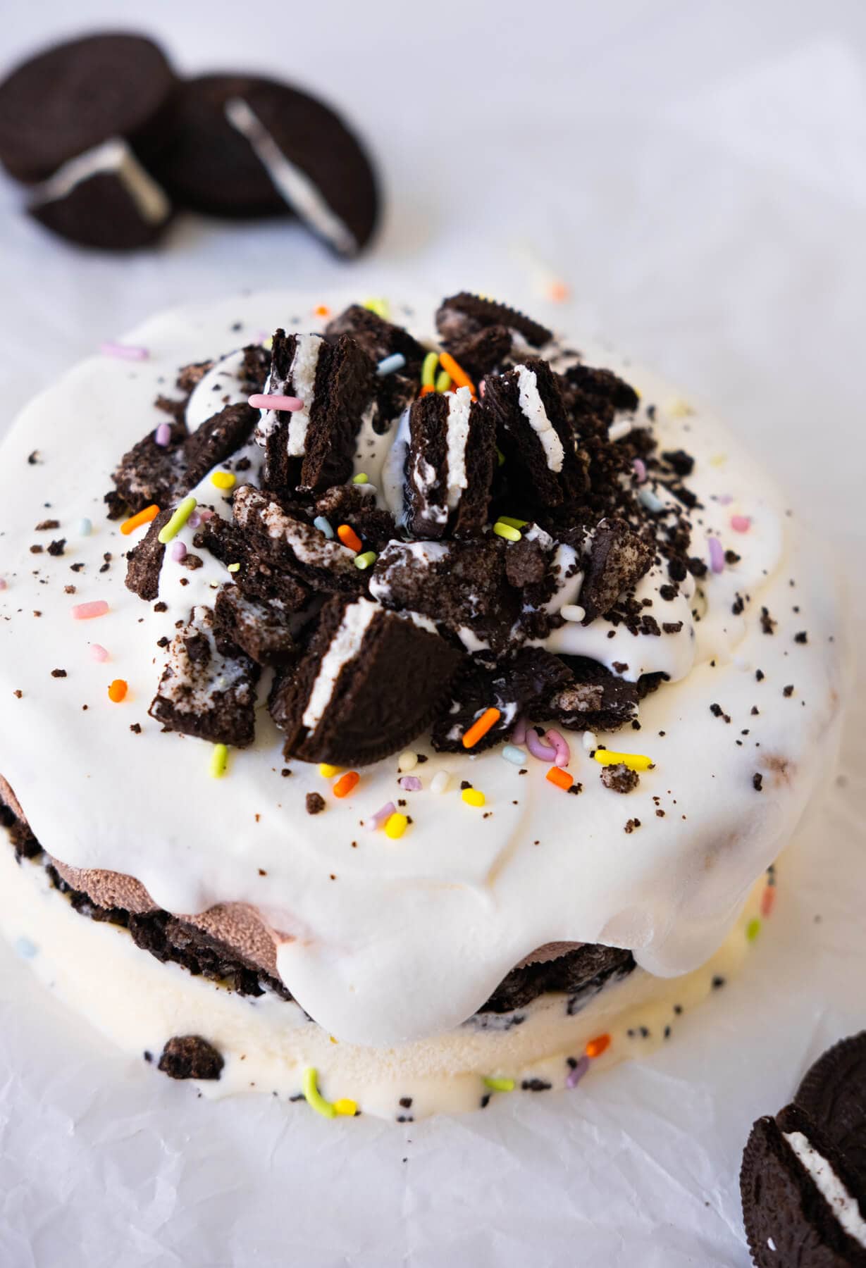 Ice cream cake filled with Oreo crumbs and topped with cookies and sprinkles.