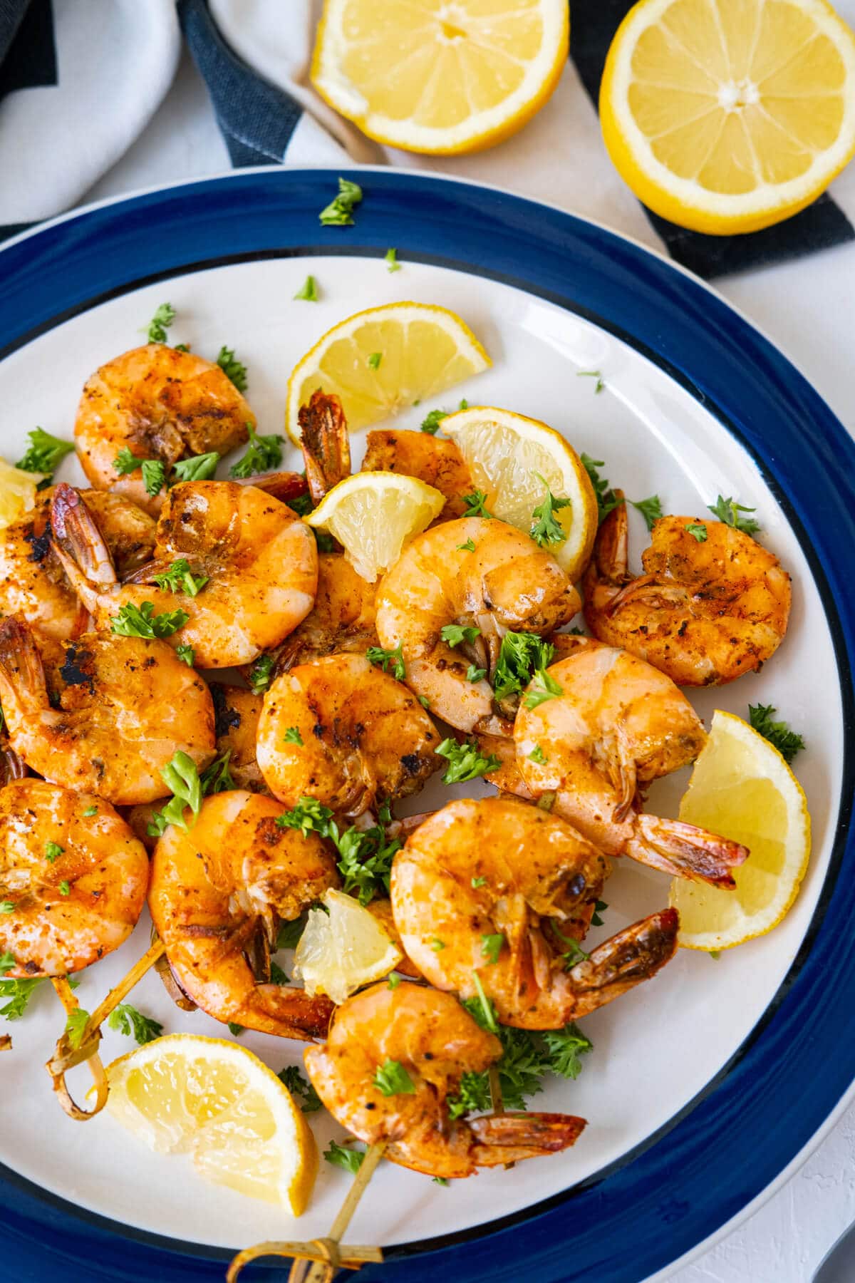 Old Bay shrimp served with lemon wedges and chopped parsley and with with half cut lemon aside.
