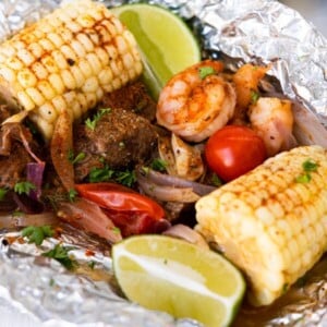 Surf'n Turf foil packs with steak, shrimp, tomatoes, corn and red onion sliced grilled.