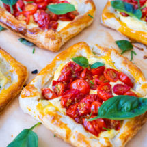 Cherry tomato tarts filled with roasted tomatoes, cream cheese and topped with fresh basil leaves.