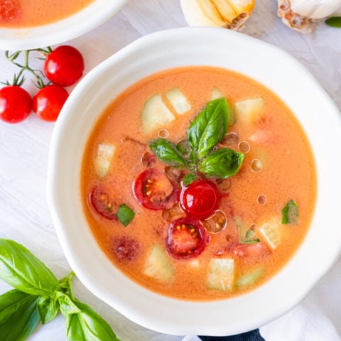 Easy chilled gazpacho topped with cherry tomatoes, cucumbers and basil leaves.