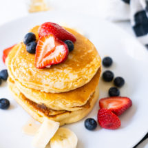 Fluffy pancakes topped with syrup, strawberries and blueberries.