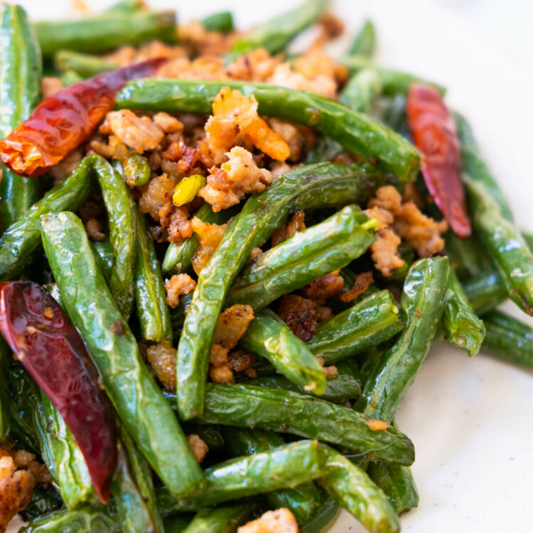 Deep-fried Sichuan green beans with dried shrimp, ground pork and dried chilies in a white platter.