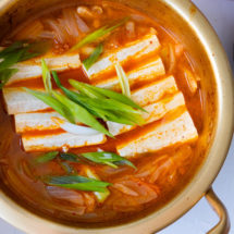 Easy kimchi jjigae with sliced firm tofu and green onion garnished on top.