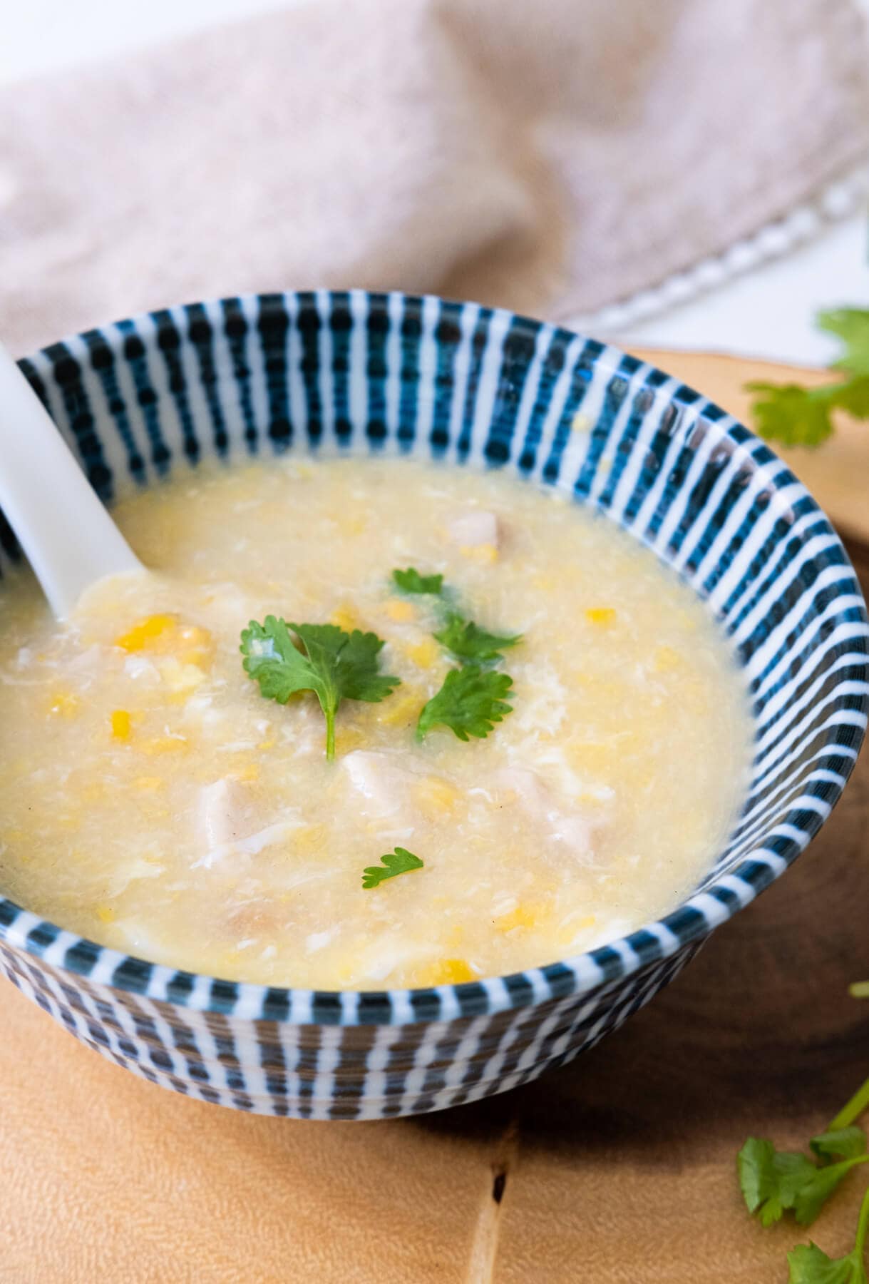 Soup with sweet corn and chicken inside with cilantro on top served in a bowl.
