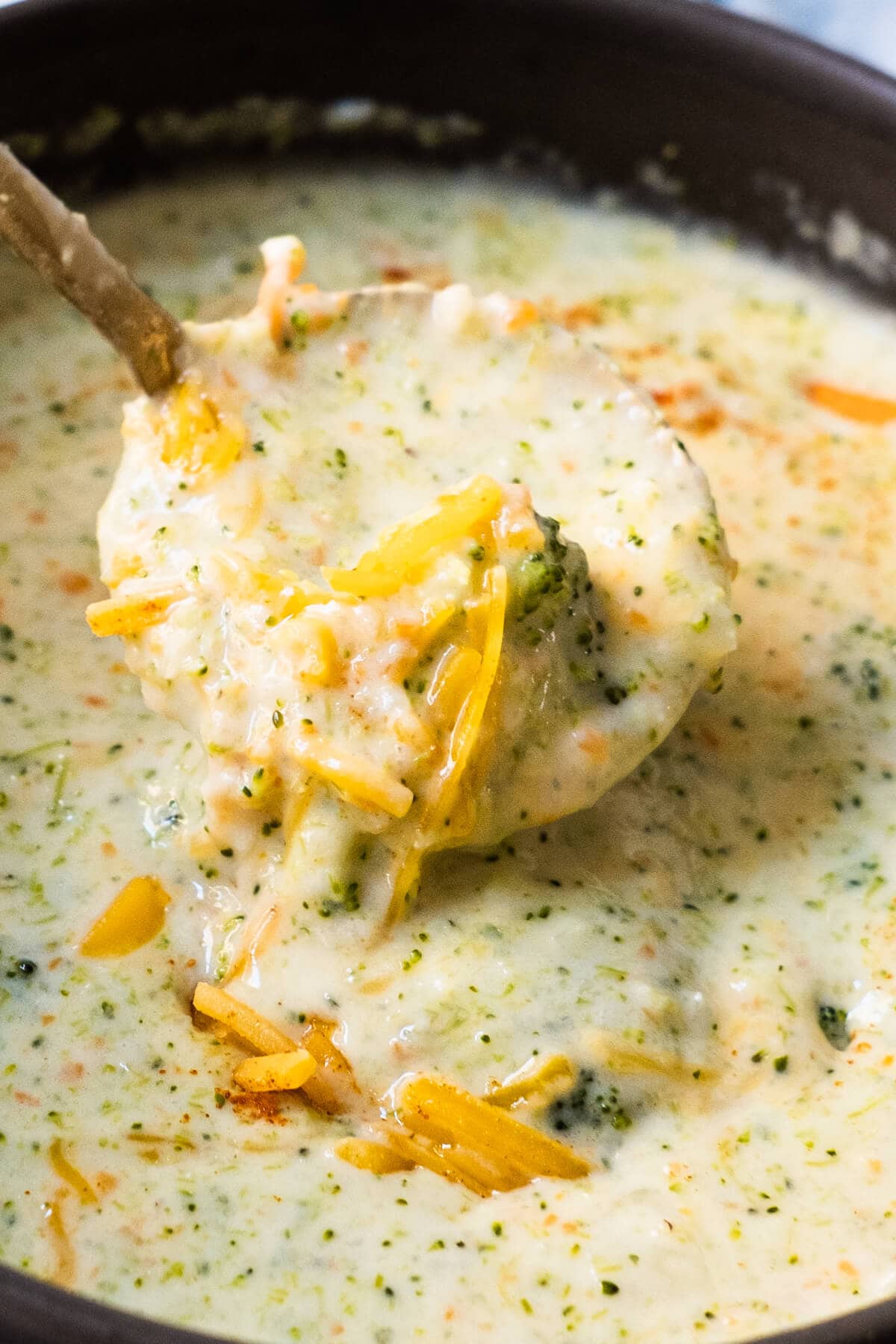Thick, creamy broccoli cheddar soup scooped by the spoon. 