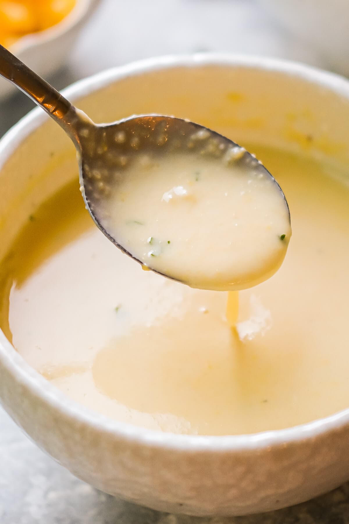 A spoon scooping creamy yellow soup out of a bowl. 