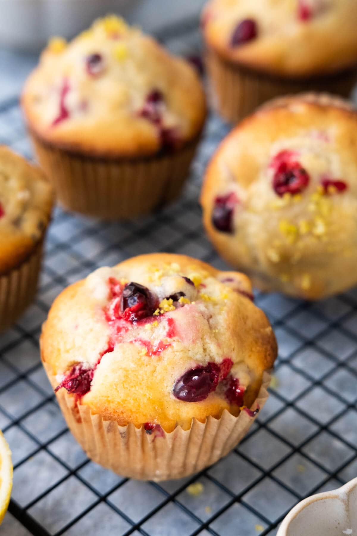 A muffin filled with juicy round cranberries and lemon zest placed on a tray. 