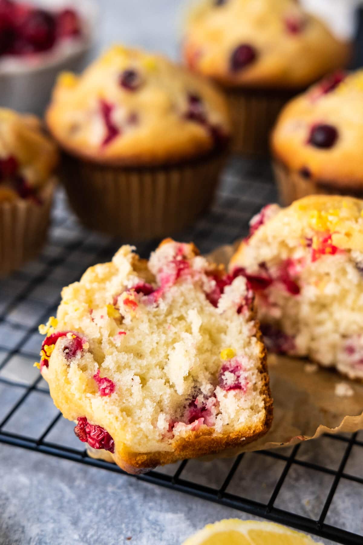 Moist, buttery cranberry lemon muffins half cut with juicy berries in the center.